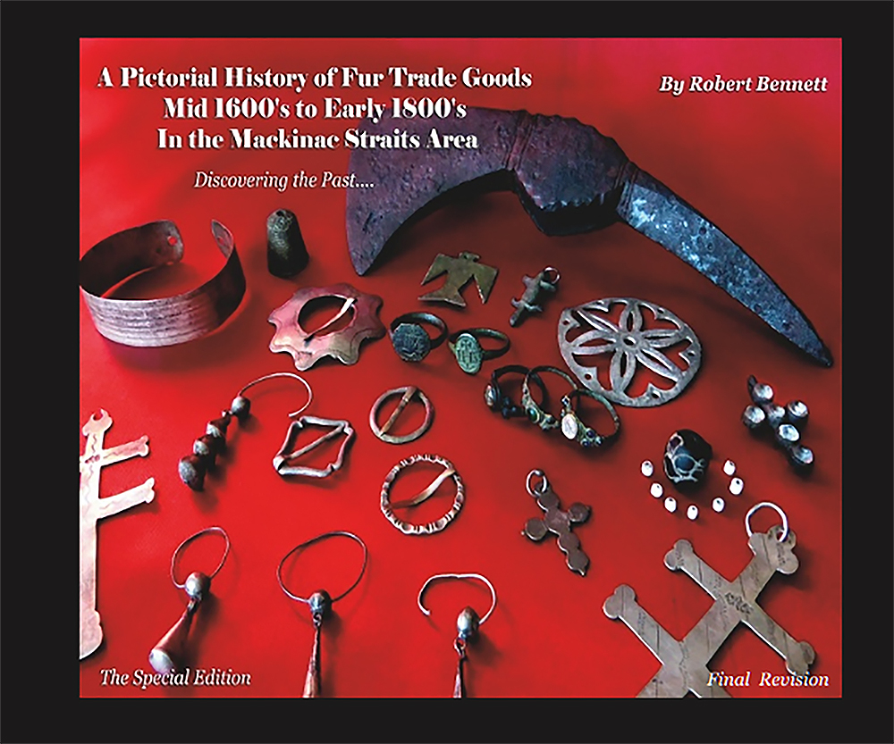 Book cover (Special Edition, Final Revision): A Pictorial History of Fur Trade Goods by Robert Bennett, showing trade rings, crosses, an axe head and silver brooches on red cloth